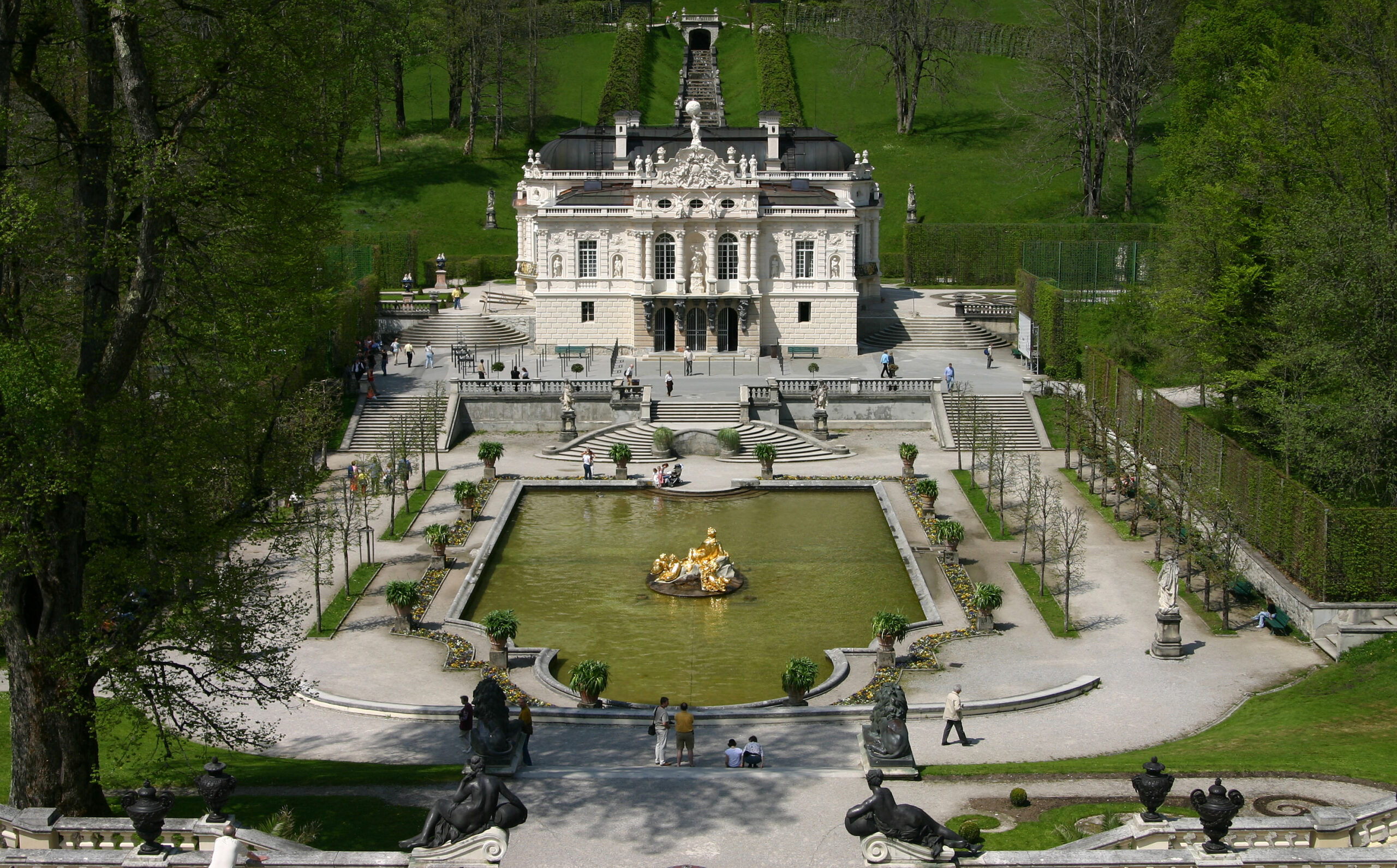 Linderhof Palace nestled in the Bavarian Alps, surrounded by manicured gardens and ornate fountains, reminiscent of Versailles.
