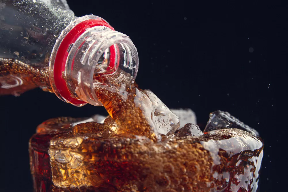 Soda Berlebih dengan ekspresi cemas memegang gelas berisi soda, simbolisasi kekhawatiran terhadap efek buruk soda pada kesehatan gigi dan berat badannya