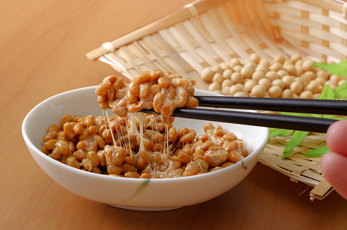 Sebuah mangkuk Manfaat Natto yang baru disiapkan, ditampilkan dengan taburan daun bawang dan saus kecap, menonjolkan tekstur lengket khas dan biji kedelai fermentasi yang sehat