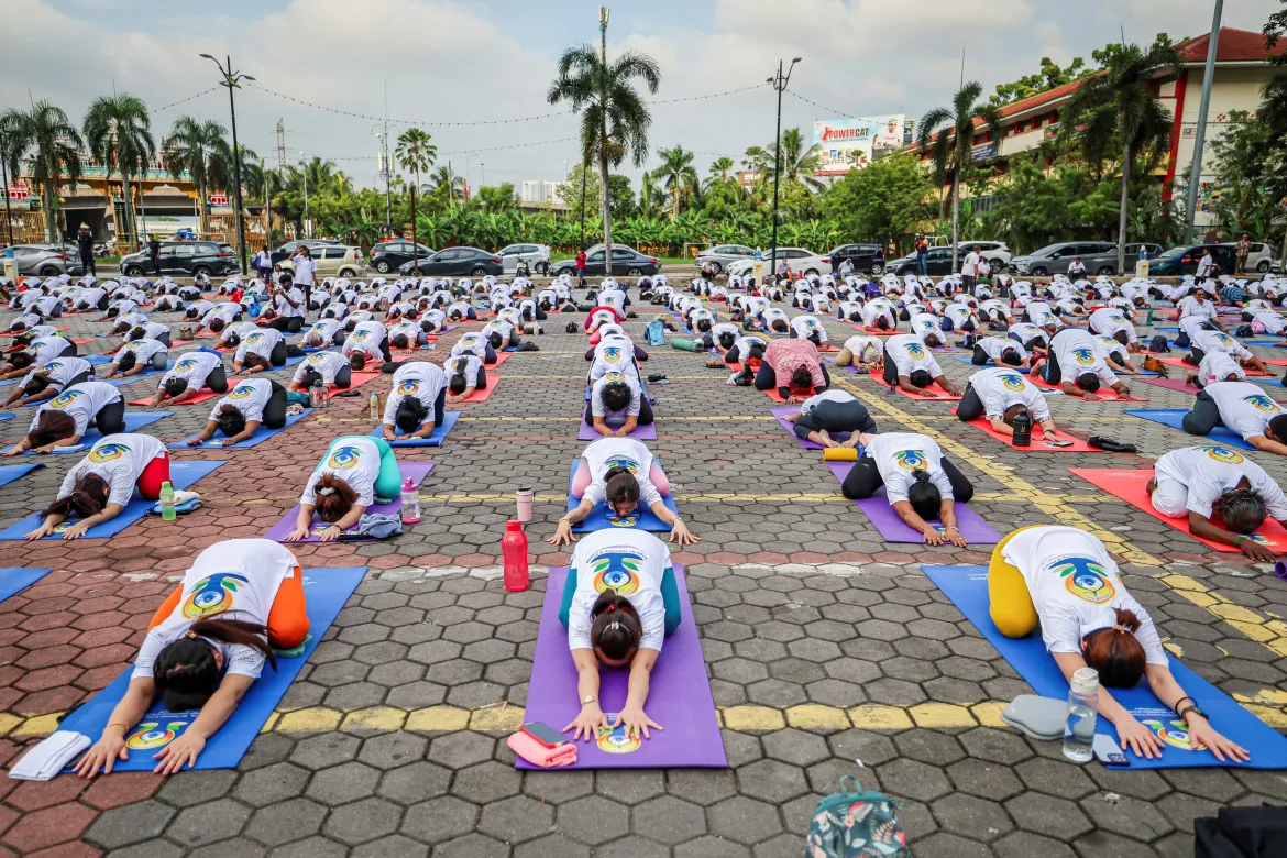Children and adults practicing yoga together in a community park on International Yoga Day.